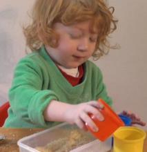 Toddler with good core stability reaching forwards in sitting